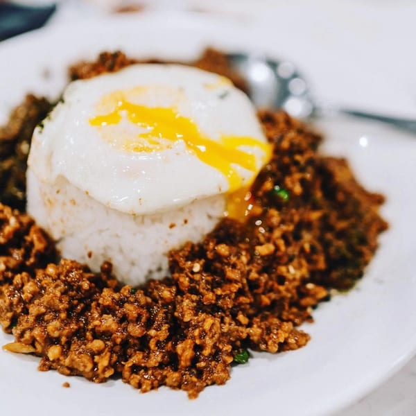 Chinese rice dish with minced meat and a fried egg with a runny yolk on a white plate.