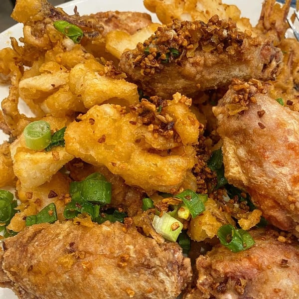 Crispy fried chicken wings and calamari, garnished with chopped green onions and fried garlic.