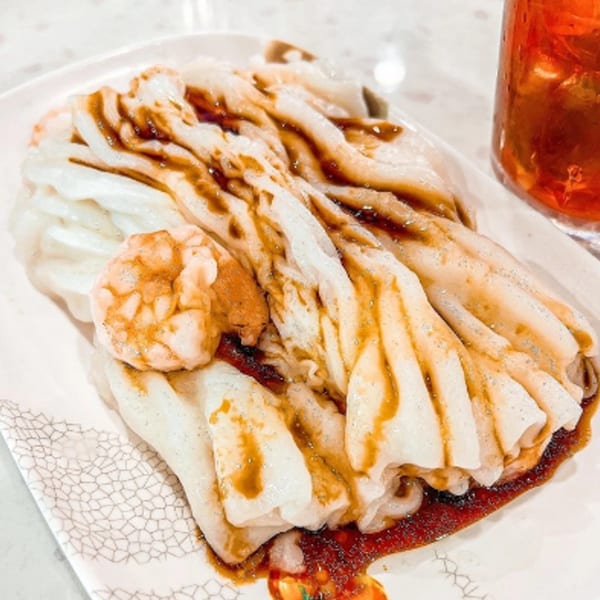 Delicious Food Corner's shrimp rice rolls with sauce, next to a glass of iced tea.